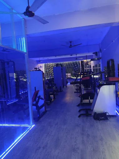 Blue-lit gym floor with cardio equipment